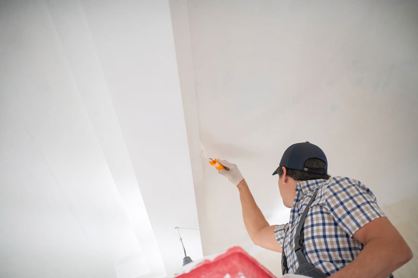 Painter rolling flat white paint on a bedroom ceiling in Raleigh