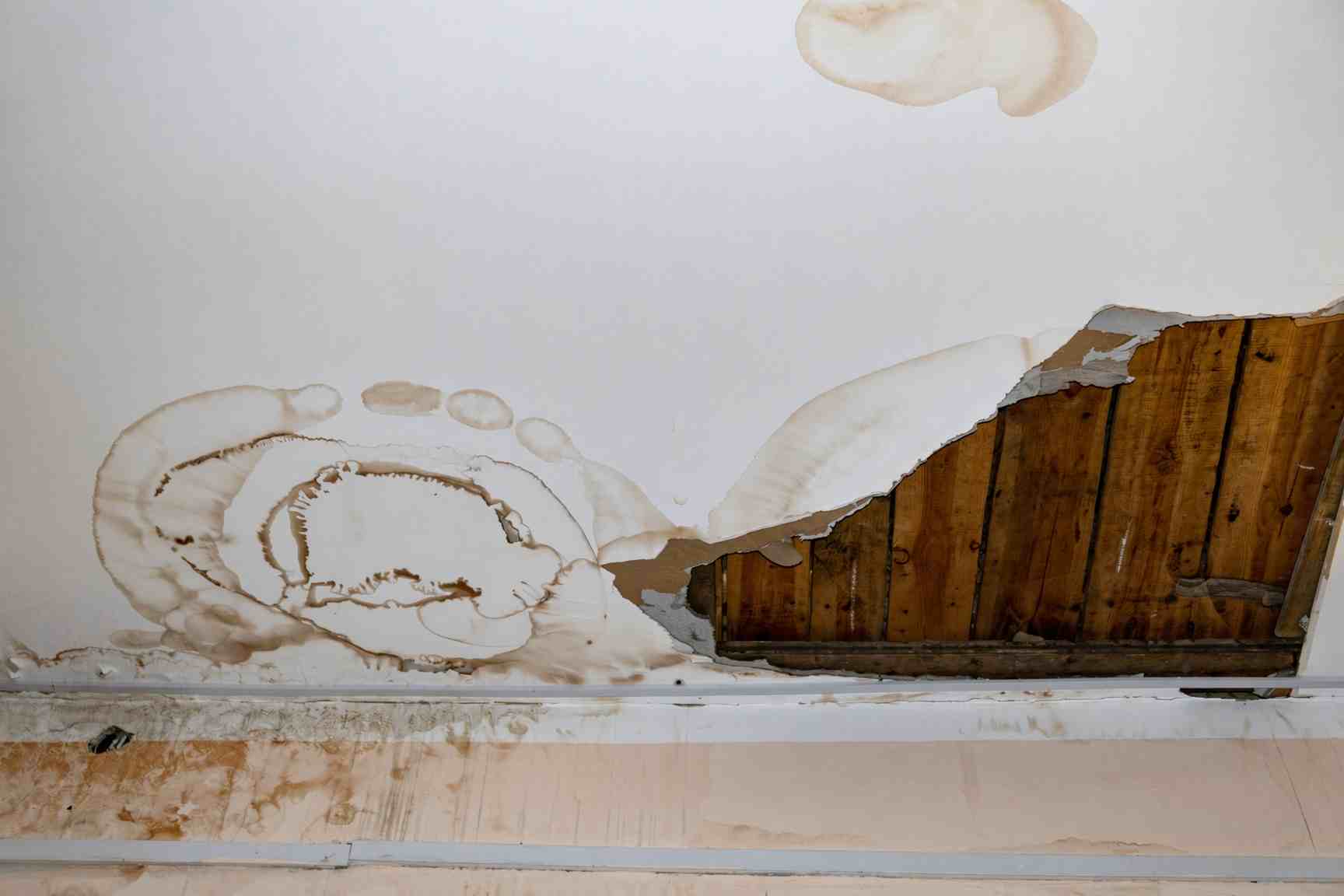 Water damaged ceiling drywall being cut out in a Raleigh home